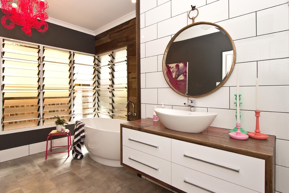 Example of a mid-sized trendy master white tile and subway tile porcelain tile bathroom design in Dunedin with wood countertops, a vessel sink, flat-panel cabinets, white cabinets and black walls