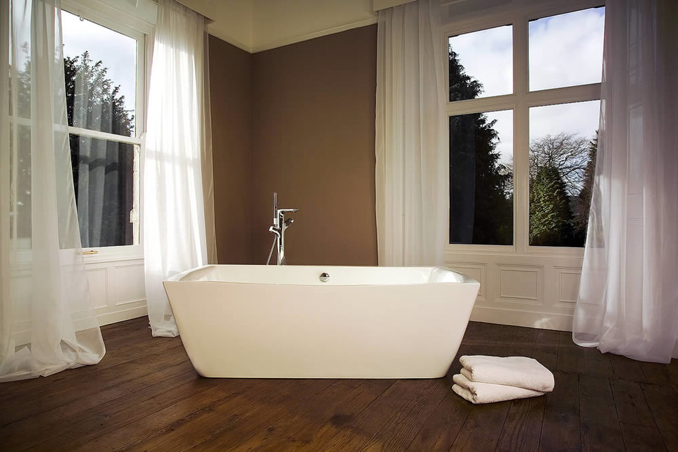Imagen de cuarto de baño contemporáneo grande con bañera exenta, paredes marrones y suelo de madera oscura