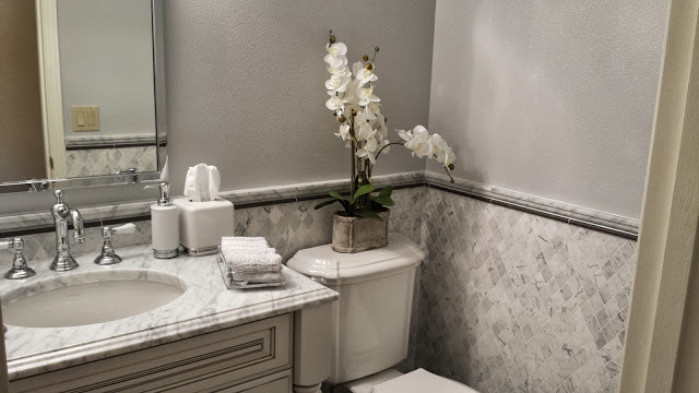 Idee per una piccola stanza da bagno con doccia chic con piastrelle grigie, ante a filo, ante bianche, WC a due pezzi, piastrelle in pietra, pareti grigie, lavabo sottopiano e top in marmo