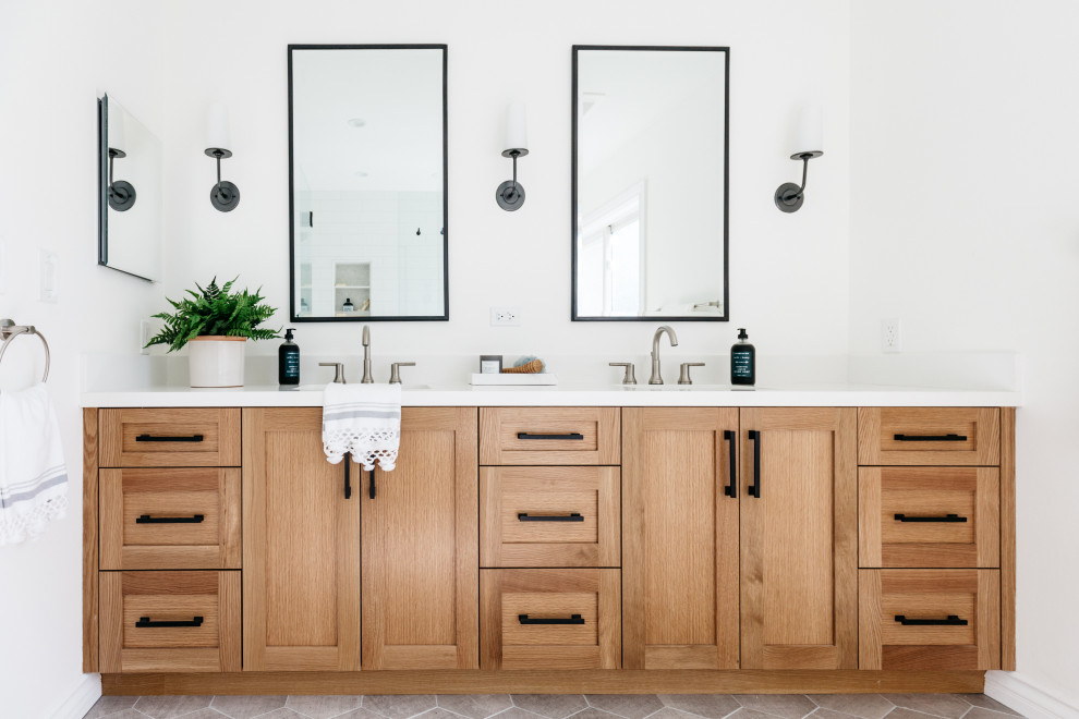 Cette image montre une salle de bain principale rustique en bois clair avec un placard à porte shaker, une douche d'angle, un carrelage blanc, un mur blanc, un sol en carrelage de porcelaine, un lavabo encastré, un plan de toilette en quartz modifié, un sol gris et un plan de toilette blanc.