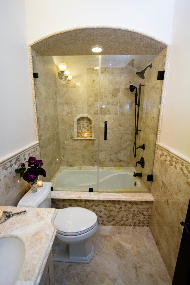 На фото: ванная комната среднего размера в средиземноморском стиле с фасадами с выступающей филенкой, бежевыми фасадами, ванной в нише, душем над ванной, унитазом-моноблоком, бежевой плиткой, коричневой плиткой, керамогранитной плиткой, белыми стенами, мраморным полом, душевой кабиной, врезной раковиной и мраморной столешницей с
