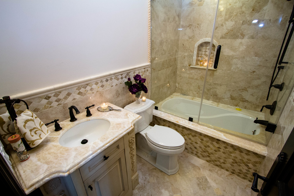 Example of a mid-sized tuscan 3/4 beige tile, brown tile and porcelain tile marble floor bathroom design in Los Angeles with raised-panel cabinets, beige cabinets, a one-piece toilet, white walls, an undermount sink and marble countertops