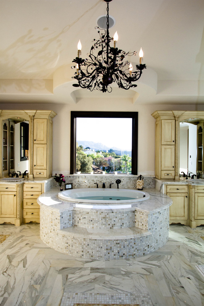 Inspiration pour une grande salle de bain principale méditerranéenne avec un placard avec porte à panneau surélevé, des portes de placard beiges, une baignoire posée, une douche d'angle, un carrelage beige, un carrelage gris, un carrelage blanc, mosaïque, un mur beige, un sol en marbre, un lavabo posé et un plan de toilette en marbre.