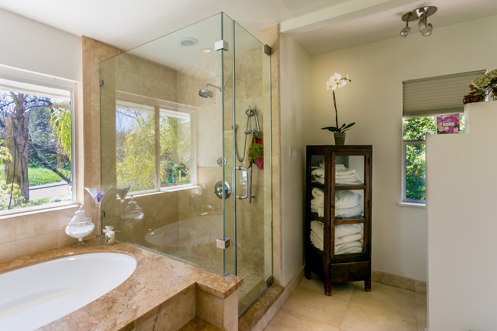 This is an example of a large contemporary ensuite bathroom in Los Angeles with a built-in sink, shaker cabinets, brown cabinets, a built-in bath, a walk-in shower, a one-piece toilet, beige tiles, stone tiles, white walls and travertine flooring.
