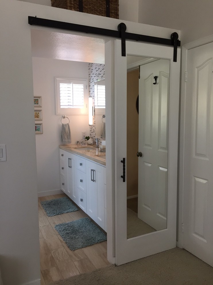 Cette photo montre une salle de bain principale chic de taille moyenne avec un placard à porte shaker, des portes de placard blanches, un carrelage multicolore, mosaïque, un mur blanc, un sol en travertin, un lavabo encastré, un plan de toilette en marbre et un sol beige.
