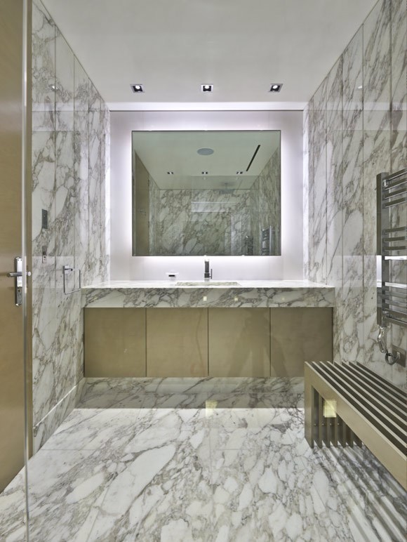 Example of a large trendy master white tile and stone slab marble floor doorless shower design in New Orleans with an undermount sink, flat-panel cabinets, brown cabinets, marble countertops and white walls
