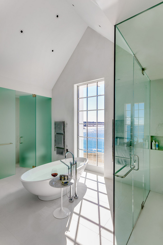 Photo of a modern ensuite bathroom in Boston with a freestanding bath, a built-in shower, white tiles, stone slabs, engineered stone worktops, white floors, a hinged door and white worktops.