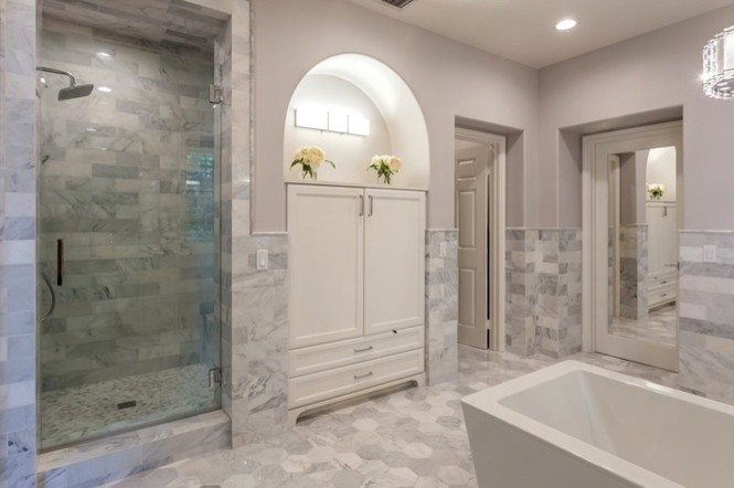 Modern inredning av ett stort en-suite badrum, med släta luckor, vita skåp, ett fristående badkar, en dusch i en alkov, en toalettstol med hel cisternkåpa, grå kakel, marmorkakel, grå väggar, marmorgolv, ett nedsänkt handfat, bänkskiva i kvarts, grått golv och dusch med gångjärnsdörr