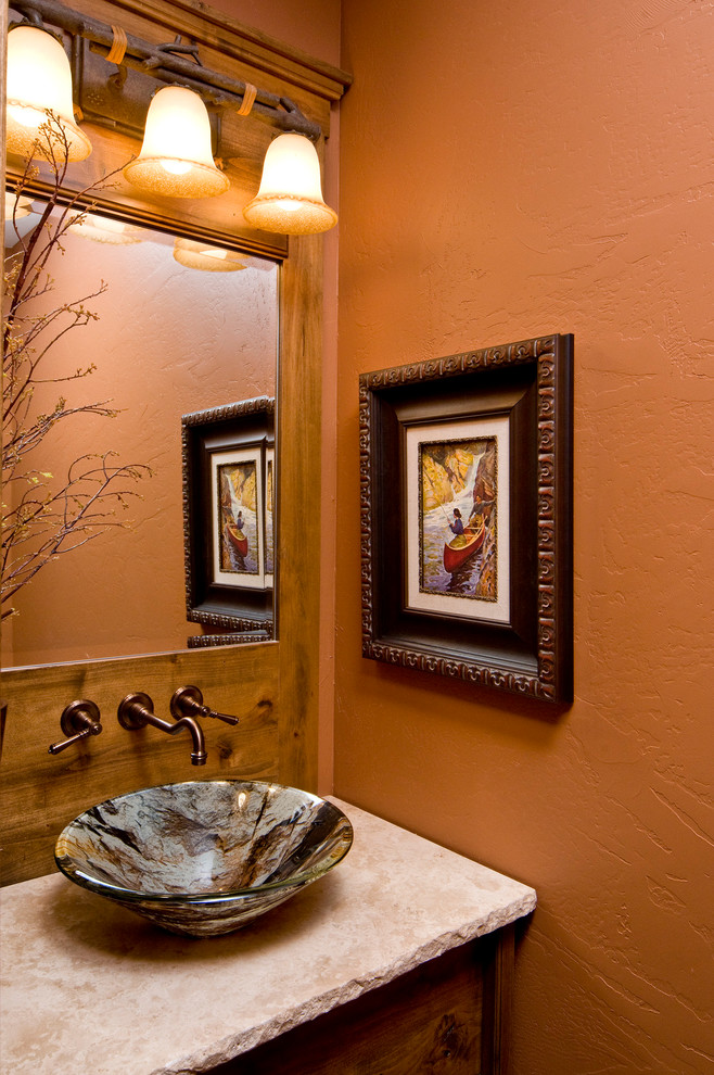 Aménagement d'un grand WC et toilettes montagne en bois brun avec une vasque, un placard avec porte à panneau surélevé, un plan de toilette en calcaire, WC séparés, un mur beige et un sol en travertin.