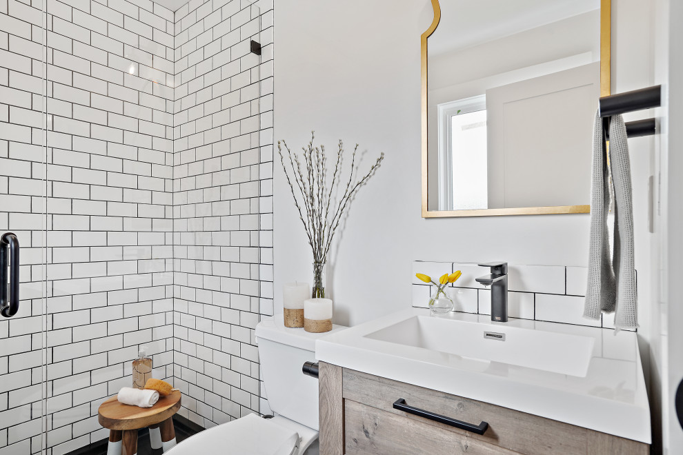 Идея дизайна: маленькая ванная комната в стиле неоклассика (современная классика) с плоскими фасадами, светлыми деревянными фасадами, душем в нише, раздельным унитазом, белой плиткой, керамической плиткой, белыми стенами, полом из керамогранита, душевой кабиной, монолитной раковиной, столешницей из ламината, черным полом, душем с распашными дверями, белой столешницей, тумбой под одну раковину и напольной тумбой для на участке и в саду