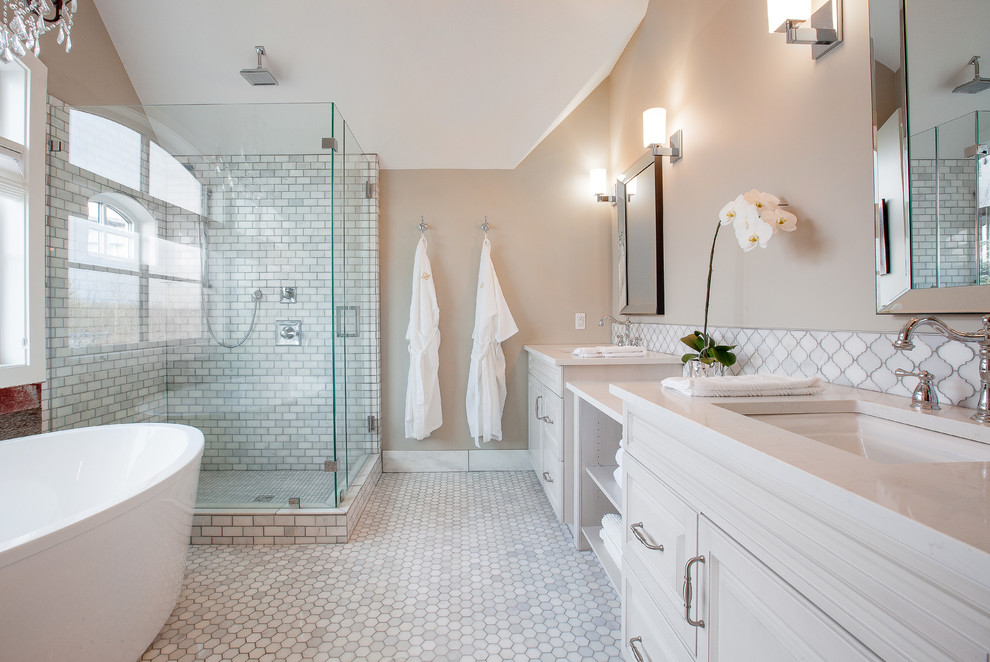 На фото: большая главная ванная комната в классическом стиле с врезной раковиной, фасадами с выступающей филенкой, бежевыми стенами, белыми фасадами, отдельно стоящей ванной, угловым душем, белой плиткой и полом из мозаичной плитки с