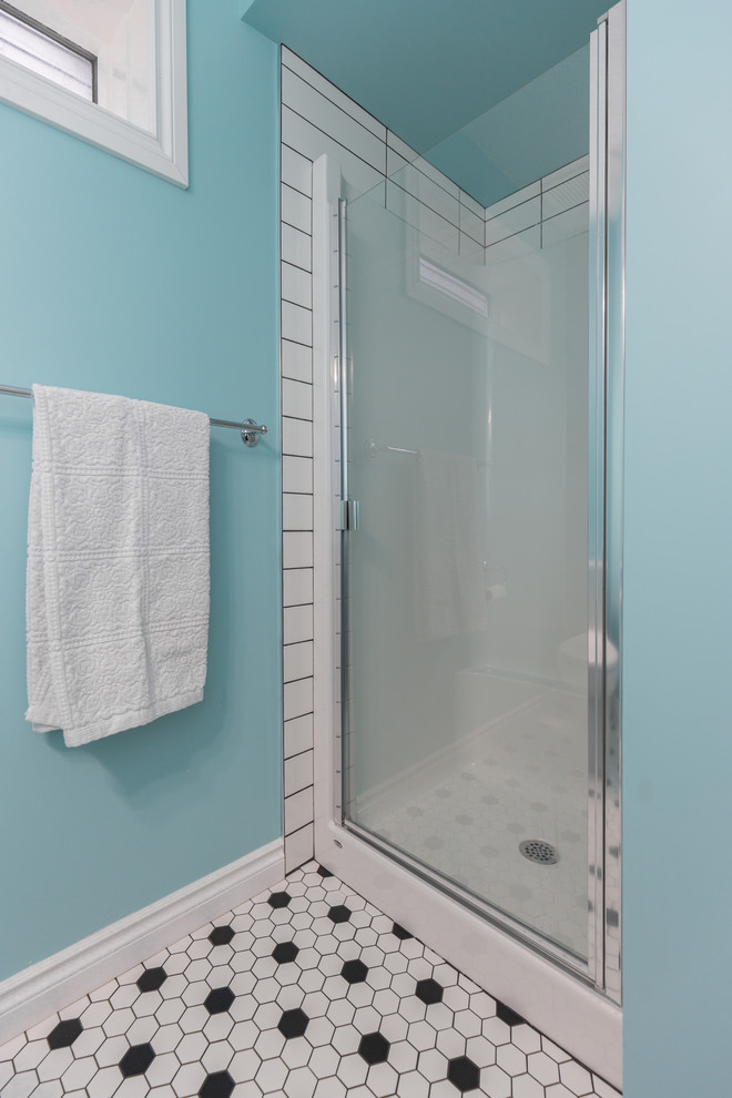 Klassisk inredning av ett stort badrum med dusch, med släta luckor, skåp i mörkt trä, en dusch i en alkov, en toalettstol med separat cisternkåpa, vit kakel, tunnelbanekakel, blå väggar, mosaikgolv, flerfärgat golv och dusch med gångjärnsdörr