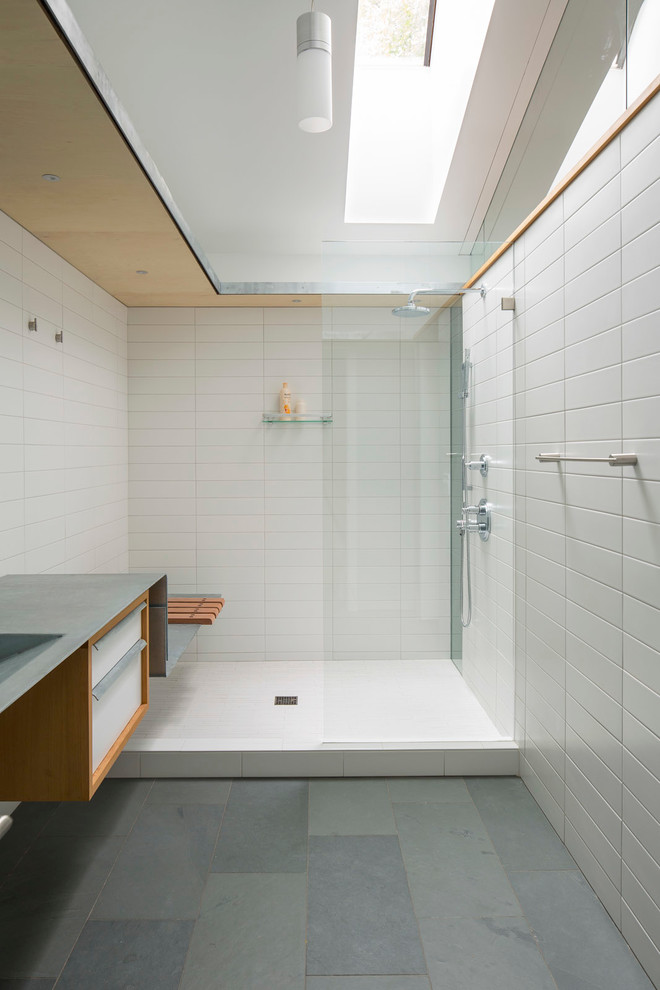 Cette photo montre une salle de bain moderne avec un lavabo intégré, un placard à porte plane, des portes de placard blanches, une douche ouverte, un carrelage blanc et un sol en ardoise.