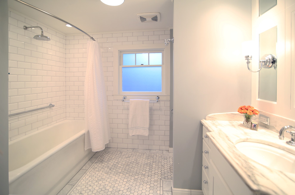 Exemple d'une salle de bain chic avec un lavabo encastré, un placard avec porte à panneau encastré, des portes de placard blanches, un plan de toilette en marbre, une baignoire en alcôve, un combiné douche/baignoire, WC à poser, un carrelage blanc et un carrelage de pierre.