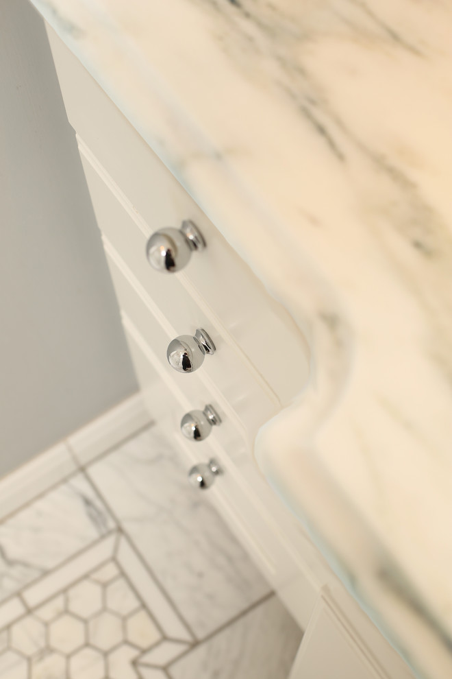 Exempel på ett klassiskt badrum, med vita skåp, marmorbänkskiva, ett badkar i en alkov, en dusch/badkar-kombination, en toalettstol med separat cisternkåpa, vit kakel, stenkakel och ett undermonterad handfat