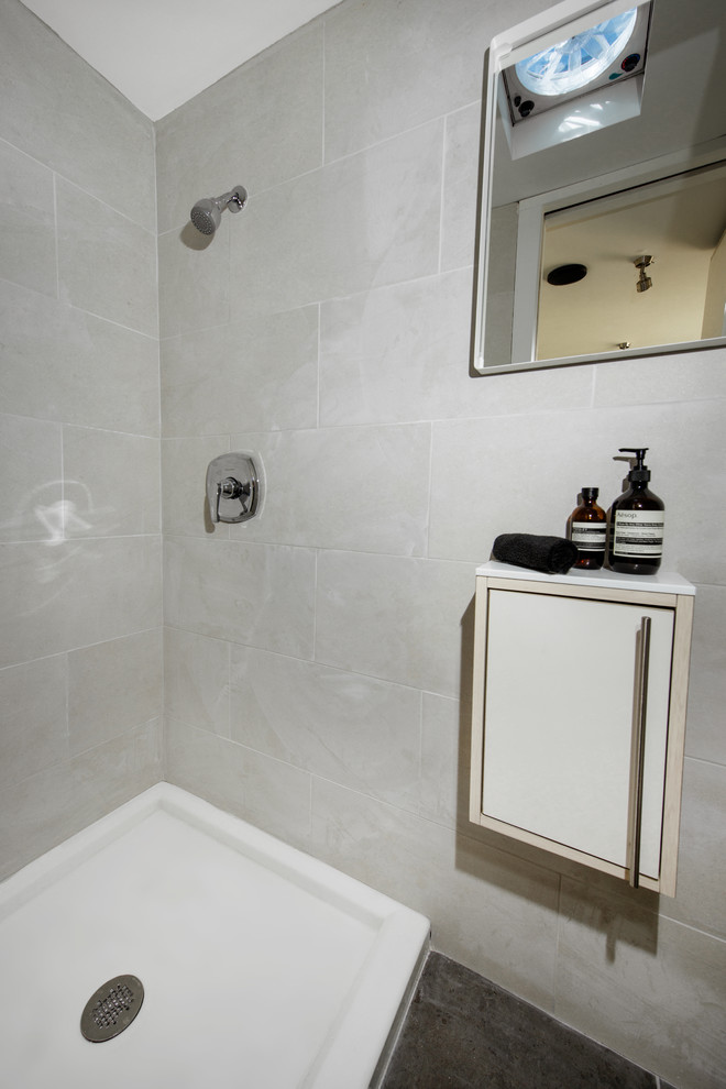 Small minimalist 3/4 beige tile and ceramic tile ceramic tile and black floor bathroom photo in Columbus with flat-panel cabinets, white cabinets, a two-piece toilet, beige walls, a wall-mount sink and solid surface countertops