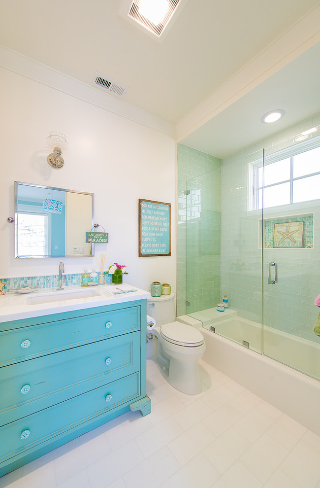 Maritimes Badezimmer En Suite mit integriertem Waschbecken, verzierten Schränken, blauen Schränken, Badewanne in Nische, Duschbadewanne, Toilette mit Aufsatzspülkasten, weißen Fliesen, Keramikfliesen, weißer Wandfarbe und Keramikboden in Los Angeles