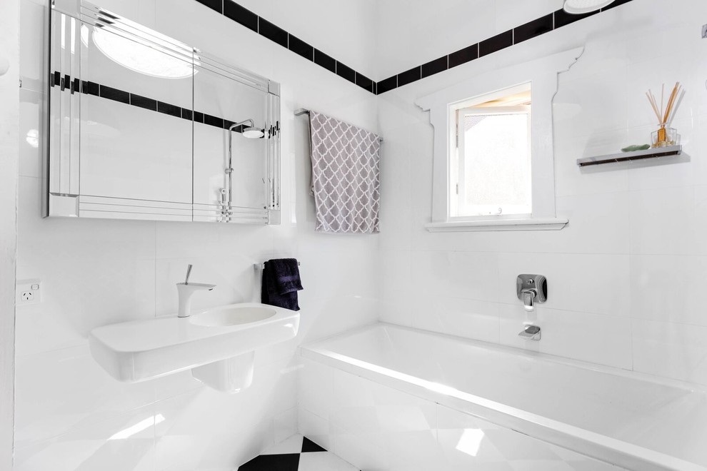 Cette image montre une petite salle de bain traditionnelle avec un lavabo suspendu, une baignoire en alcôve et un mur blanc.