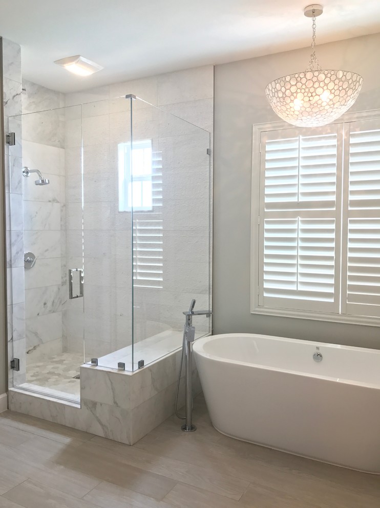 Design ideas for a medium sized country ensuite bathroom in Orange County with raised-panel cabinets, white cabinets, a freestanding bath, a corner shower, white tiles, marble tiles, grey walls, a submerged sink and a hinged door.