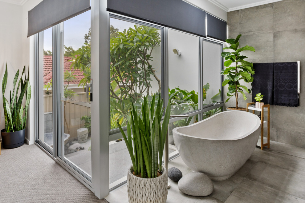 Modelo de cuarto de baño actual con bañera exenta, baldosas y/o azulejos grises, paredes blancas y suelo gris