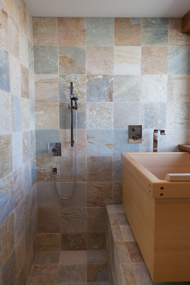 Modelo de cuarto de baño moderno con bañera japonesa, ducha abierta y suelo de pizarra
