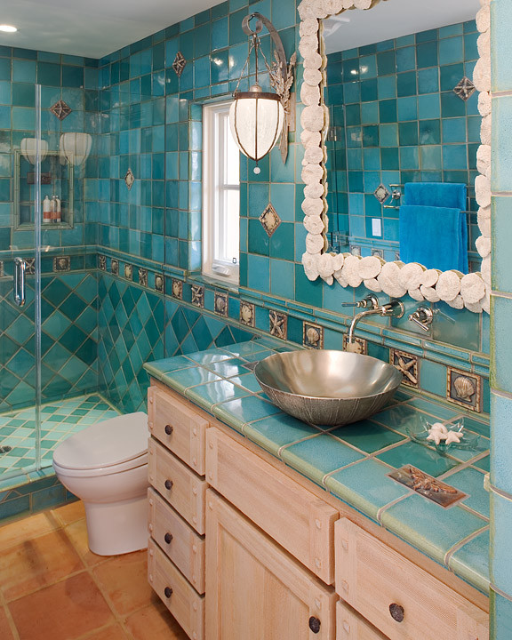 Mid-sized beach style multicolored tile and ceramic tile terra-cotta tile doorless shower photo in Santa Barbara with flat-panel cabinets, light wood cabinets, tile countertops, a one-piece toilet and blue walls