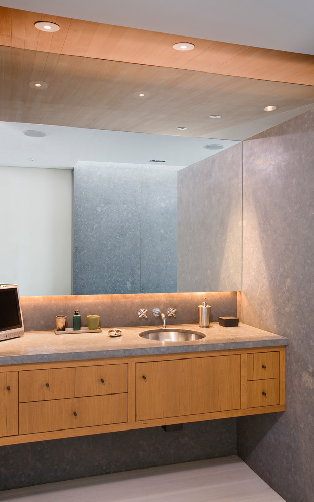 Foto di una stanza da bagno minimal con lavabo sottopiano, ante lisce, ante in legno scuro, pareti grigie e top grigio