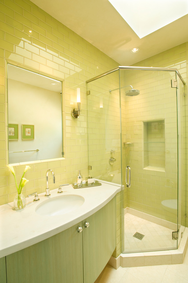На фото: детская ванная комната среднего размера в стиле неоклассика (современная классика) с плоскими фасадами, фасадами цвета дерева среднего тона, угловым душем, унитазом-моноблоком, желтой плиткой, стеклянной плиткой, желтыми стенами, полом из известняка, врезной раковиной и столешницей из известняка с