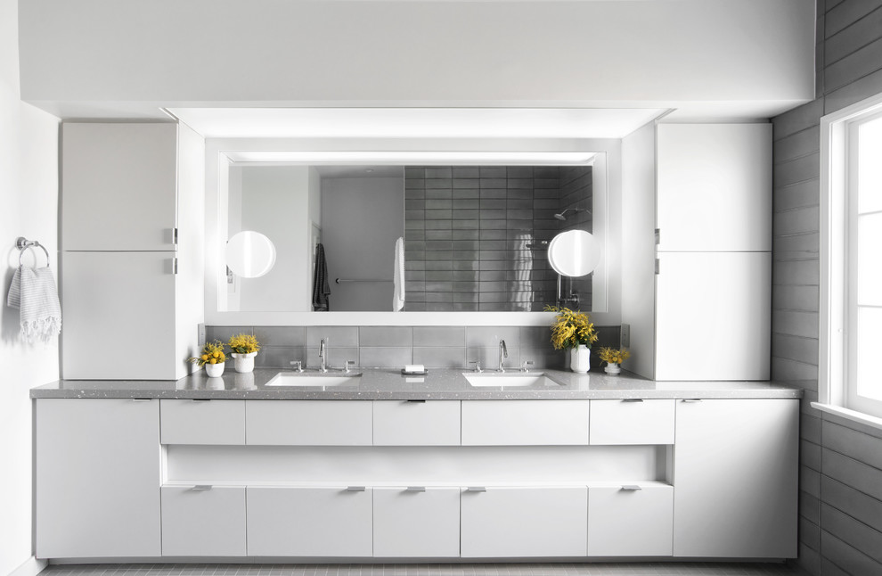 Modelo de cuarto de baño principal actual con armarios con paneles lisos, puertas de armario blancas, baldosas y/o azulejos grises, lavabo bajoencimera, suelo gris, encimeras grises y paredes grises