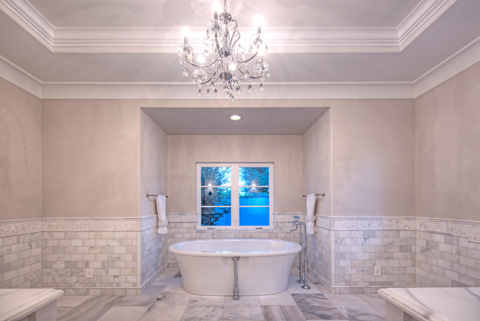 Свежая идея для дизайна: огромная главная ванная комната в классическом стиле с фасадами с утопленной филенкой, белыми фасадами, отдельно стоящей ванной, душем в нише, раздельным унитазом, серой плиткой, белой плиткой, каменной плиткой, бежевыми стенами, мраморным полом, врезной раковиной и мраморной столешницей - отличное фото интерьера