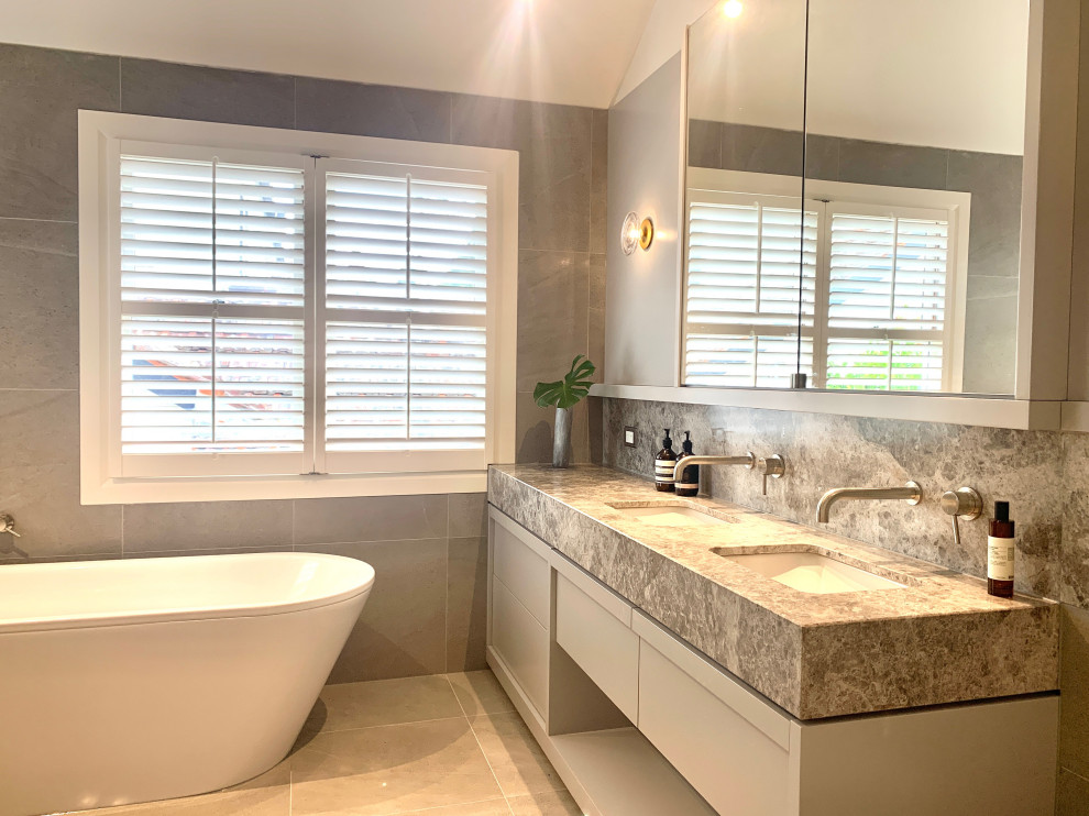 Inspiration for a medium sized traditional family bathroom in Melbourne with shaker cabinets, grey cabinets, a freestanding bath, a walk-in shower, a wall mounted toilet, grey tiles, ceramic tiles, grey walls, ceramic flooring, a built-in sink, grey floors, an open shower and multi-coloured worktops.