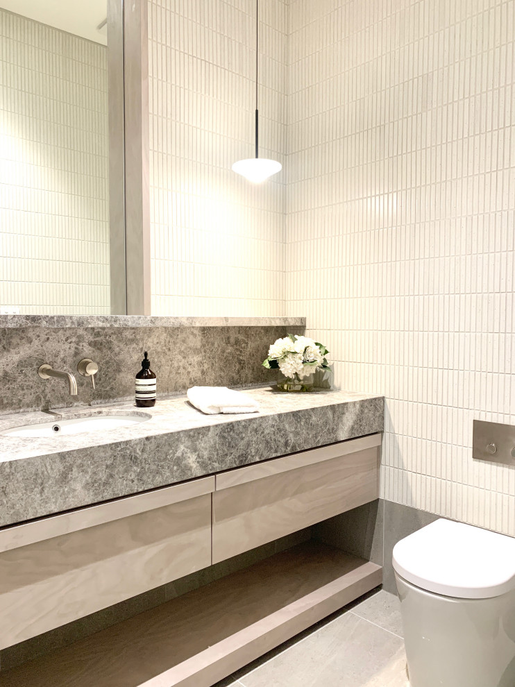 Photo of a medium sized classic family bathroom in Melbourne with shaker cabinets, grey cabinets, a freestanding bath, a walk-in shower, a wall mounted toilet, grey tiles, ceramic tiles, grey walls, ceramic flooring, a built-in sink, grey floors, an open shower and multi-coloured worktops.