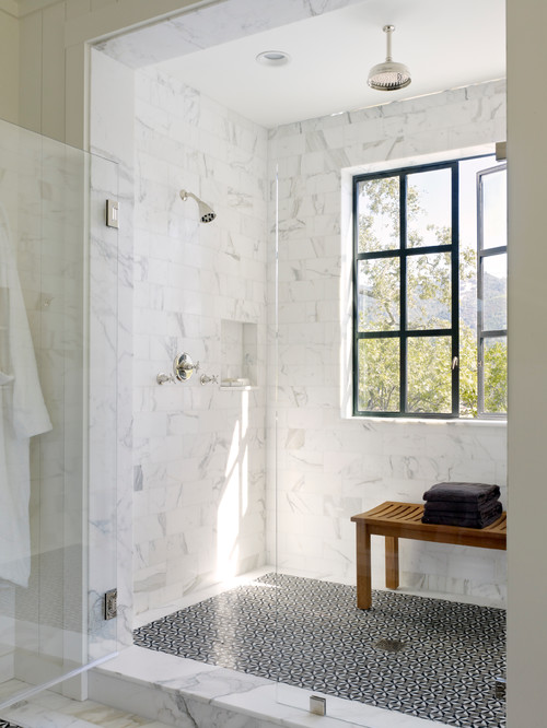 a country alcove shower design, window in shower, glass shower door, black floor tile, marble shower tile