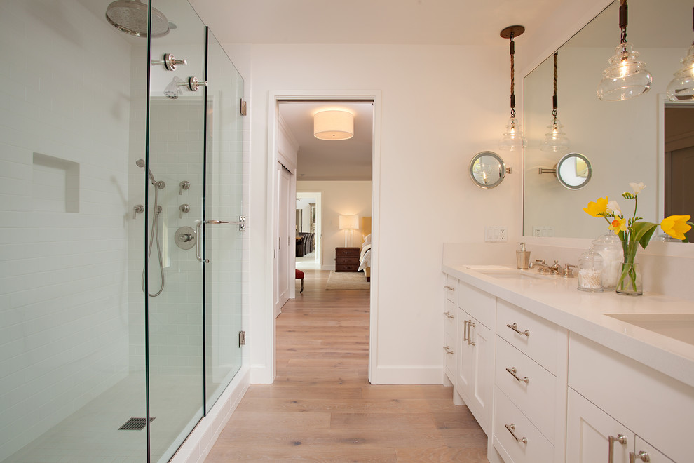 Design ideas for a large modern ensuite bathroom in San Francisco with shaker cabinets, white cabinets, an alcove shower, white tiles, white walls, light hardwood flooring, a submerged sink and engineered stone worktops.
