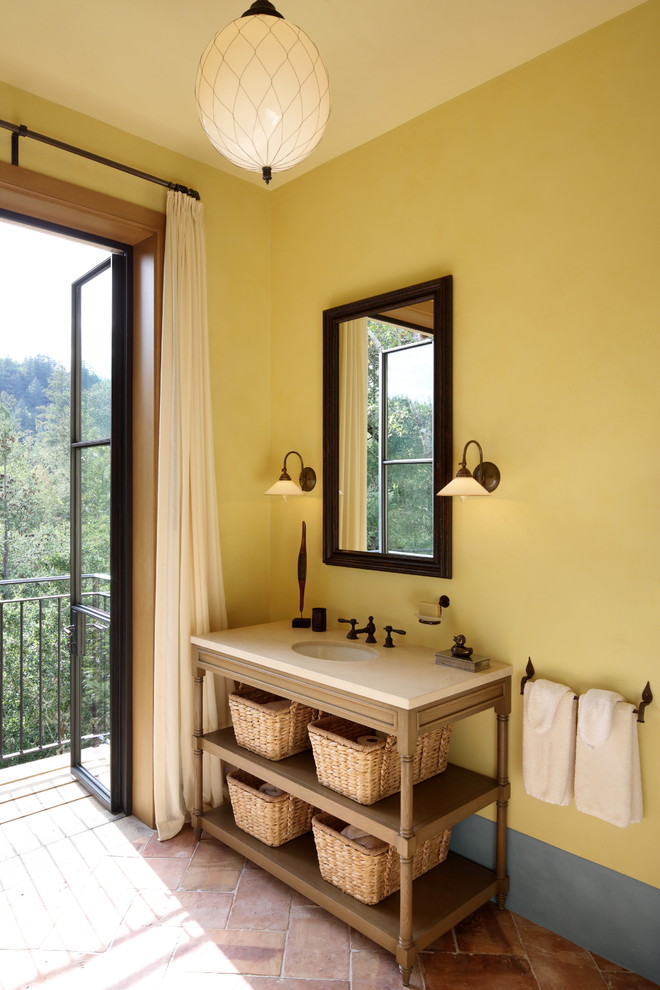 Imagen de cuarto de baño mediterráneo con paredes amarillas y suelo marrón