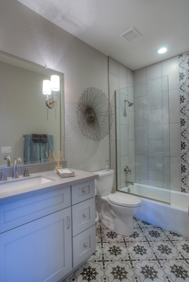 На фото: ванная комната среднего размера в стиле модернизм с фасадами в стиле шейкер, белыми фасадами, ванной в нише, душем над ванной, унитазом-моноблоком, разноцветной плиткой, керамической плиткой, бежевыми стенами, полом из линолеума, врезной раковиной, разноцветным полом и душем с раздвижными дверями с
