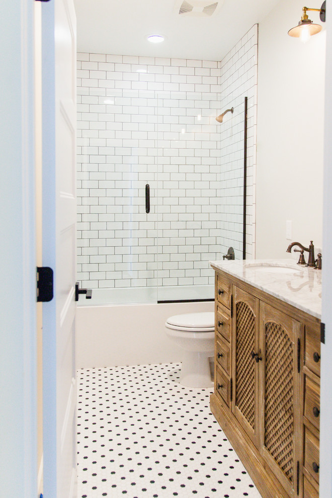 Пример оригинального дизайна: маленькая ванная комната в стиле кантри с фасадами островного типа, искусственно-состаренными фасадами, душем над ванной, раздельным унитазом, белой плиткой, плиткой кабанчик, серыми стенами, полом из керамогранита, врезной раковиной и мраморной столешницей для на участке и в саду