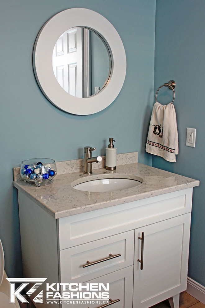 Exemple d'une salle d'eau tendance de taille moyenne avec un placard à porte shaker, des portes de placard blanches, WC à poser, un mur bleu, parquet clair, un lavabo encastré et un plan de toilette en quartz modifié.
