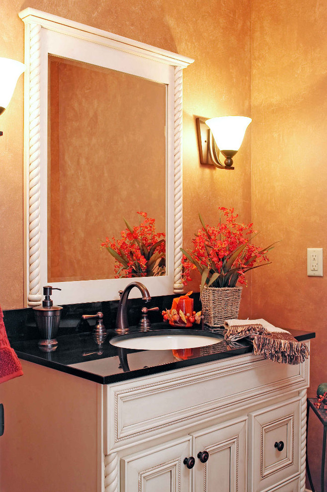 Cette photo montre une salle d'eau chic de taille moyenne avec un placard à porte affleurante, des portes de placard blanches, un mur orange, un lavabo encastré et un plan de toilette en quartz modifié.