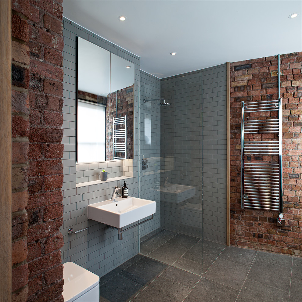 Contemporary bathroom in London with a wall-mounted sink, a corner shower, grey tiles, metro tiles and grey walls.