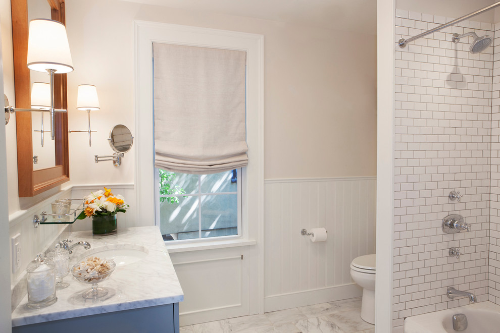 Foto på ett mellanstort vintage vit en-suite badrum, med luckor med profilerade fronter, grå skåp, ett badkar i en alkov, en dusch/badkar-kombination, vit kakel, tunnelbanekakel, vita väggar, marmorgolv, ett undermonterad handfat, marmorbänkskiva, vitt golv och dusch med duschdraperi