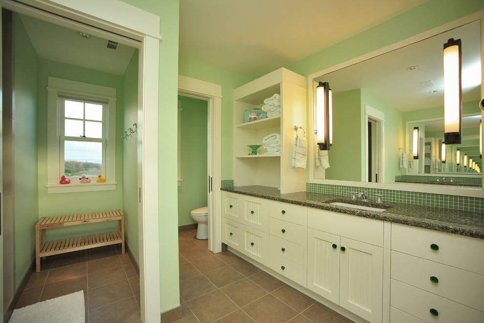 Bild på ett stort rustikt grön grönt en-suite badrum, med luckor med infälld panel, vita skåp, en toalettstol med separat cisternkåpa, grön kakel, mosaik, gröna väggar, klinkergolv i porslin, ett undermonterad handfat, bänkskiva i återvunnet glas och brunt golv