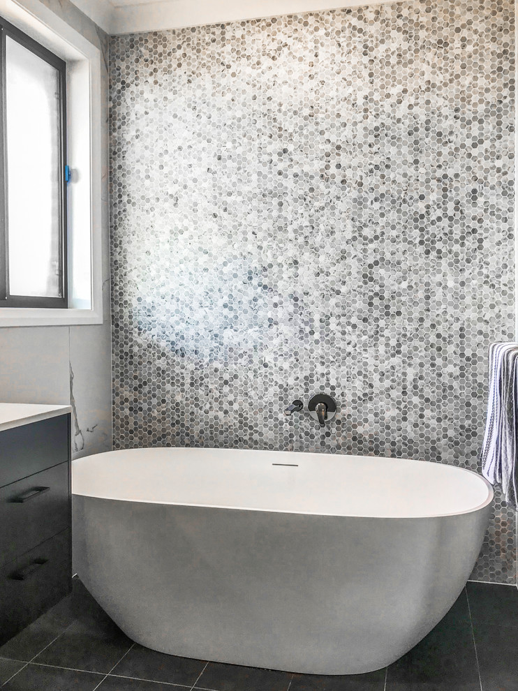 Bild på ett funkis badrum, med ett fristående badkar och svart golv