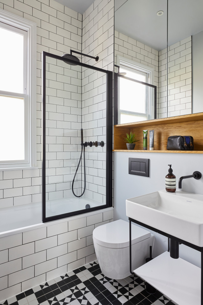 Example of a trendy 3/4 black and white tile and subway tile multicolored floor and single-sink bathroom design in London with open cabinets, white cabinets, a one-piece toilet, white walls, an integrated sink, a hinged shower door and a built-in vanity