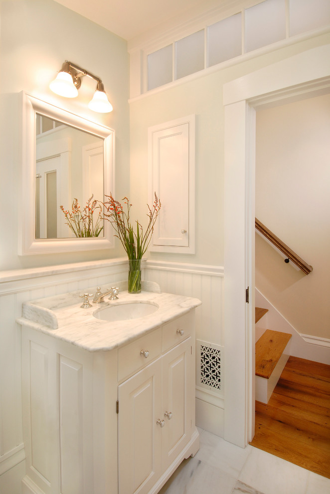 Exempel på ett mellanstort klassiskt badrum, med luckor med upphöjd panel, vita skåp, ett badkar i en alkov, en dusch/badkar-kombination, en toalettstol med separat cisternkåpa, vita väggar, marmorgolv, ett undermonterad handfat och marmorbänkskiva