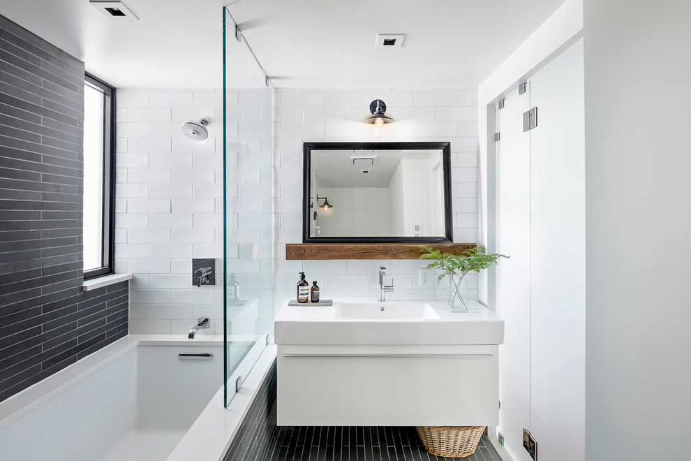 Idéer för att renovera ett funkis badrum, med ett integrerad handfat, släta luckor, vita skåp, en dusch/badkar-kombination, svart och vit kakel, vita väggar och ett undermonterat badkar