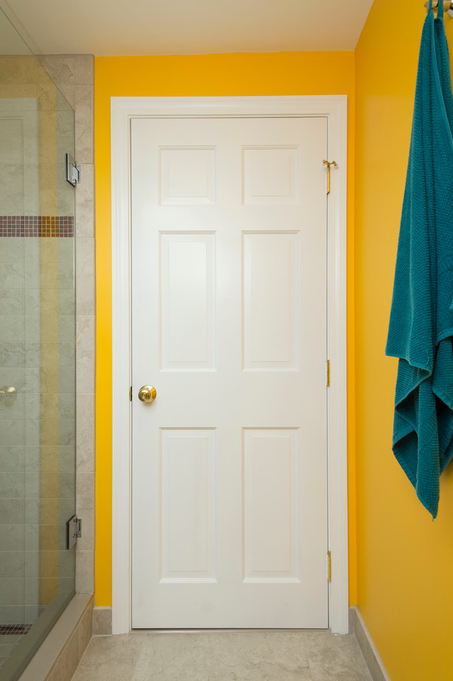 Modern inredning av ett litet badrum med dusch, med en hörndusch, en toalettstol med separat cisternkåpa, beige kakel, keramikplattor, gula väggar, klinkergolv i keramik och ett konsol handfat