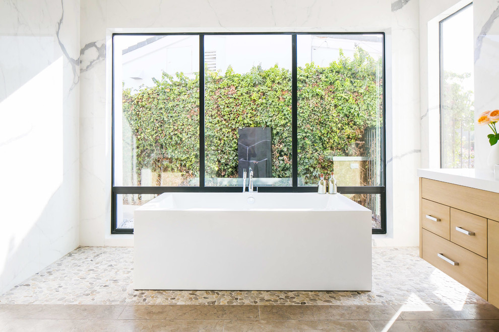 Bild på ett funkis badrum, med ett fristående badkar, vita väggar och klinkergolv i småsten