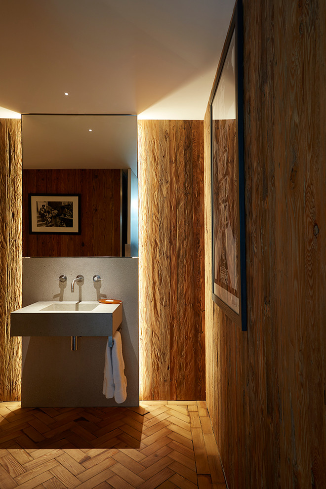 Idées déco pour une salle de bain industrielle de taille moyenne avec des portes de placard grises, un mur marron, un sol en bois brun, un lavabo suspendu et un sol marron.