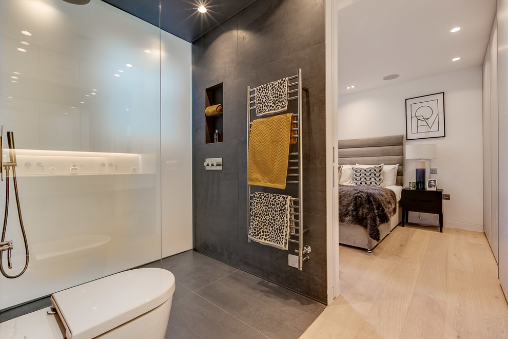 Modelo de cuarto de baño principal contemporáneo con sanitario de pared, ducha a ras de suelo, baldosas y/o azulejos grises, paredes grises, suelo gris y ducha abierta